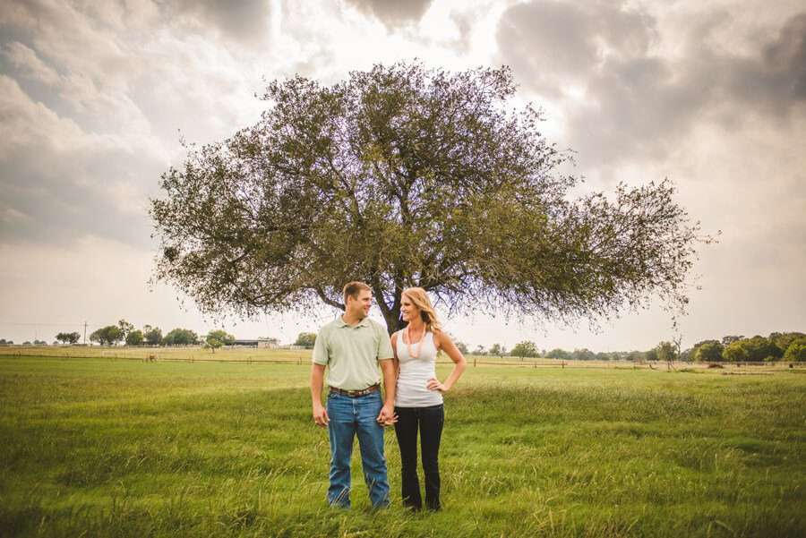 Engagement session outdoors country style in San Antonio Texas. Couple wearing dress, jeans, hats, and blue tones.